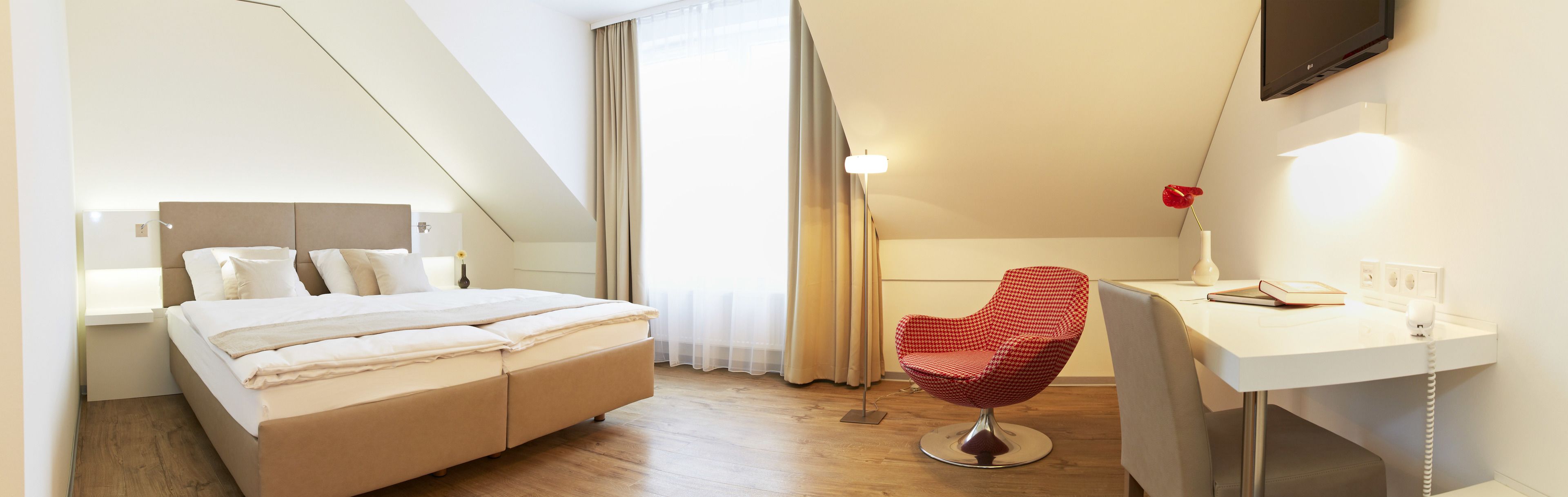 Una habitación de hotel moderna con cama, escritorio, silla y televisor.