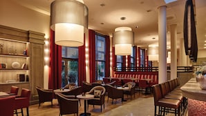 Een modern restaurant met hoge plafonds, grote hanglampen en een mix aan zitplaatsen, waaronder booths en tafels.