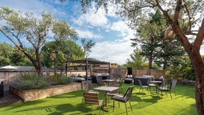 Un espace extérieur aménagé avec soin, comprenant une terrasse, un jardin en pierre, une plateforme en bois et du mobilier d’extérieur.