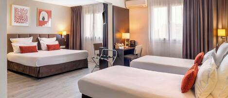Habitación de hotel con dos camas, un escritorio y una silla. Hay cortinas, cuadros en la pared y un equipo de aire acondicionado.