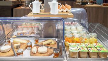 Un buffet de petit-déjeuner proposant une variété de fromages, de confitures et de yaourts en verrines.