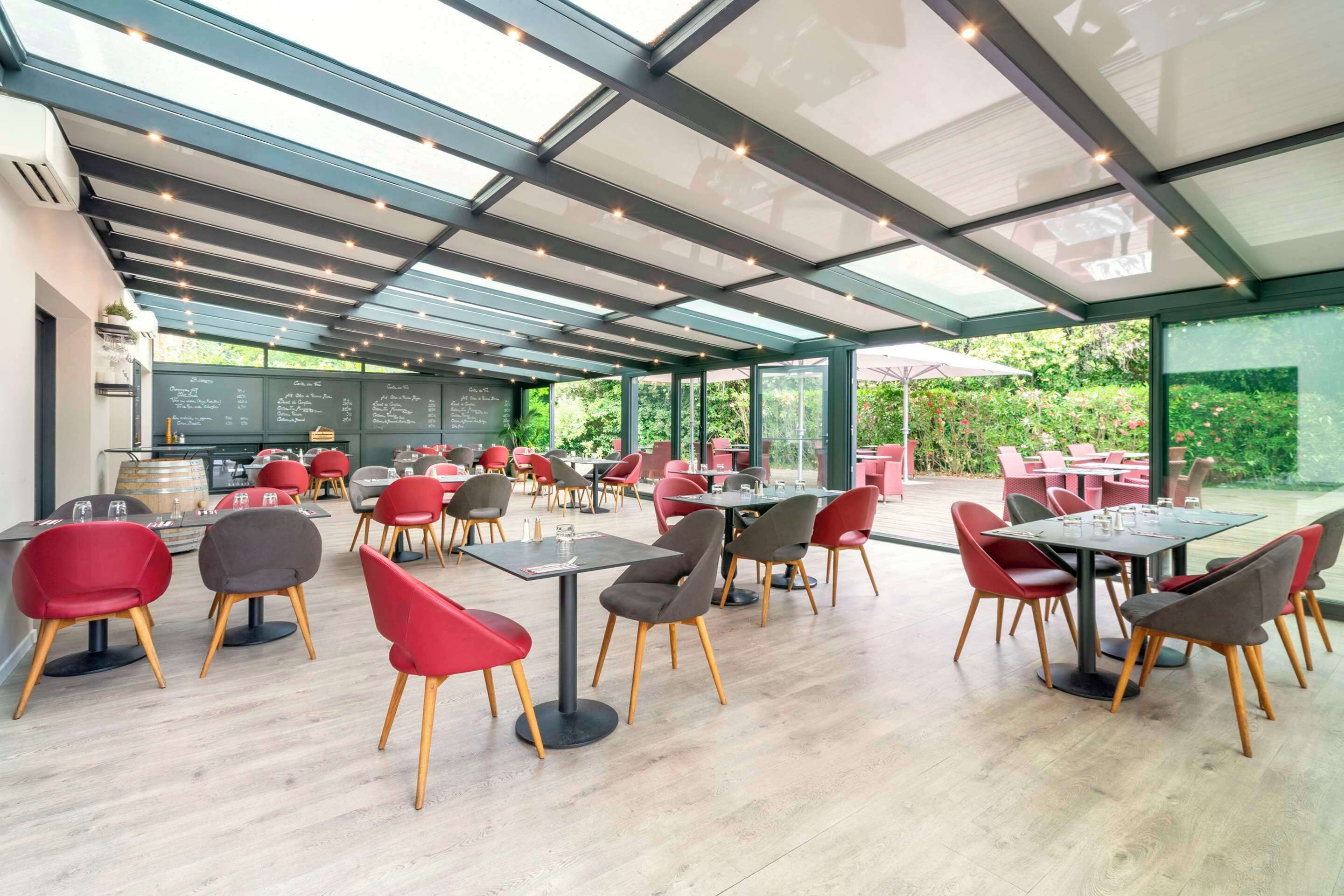 A spacious outdoor dining area with modern furniture and a glass ceiling.
