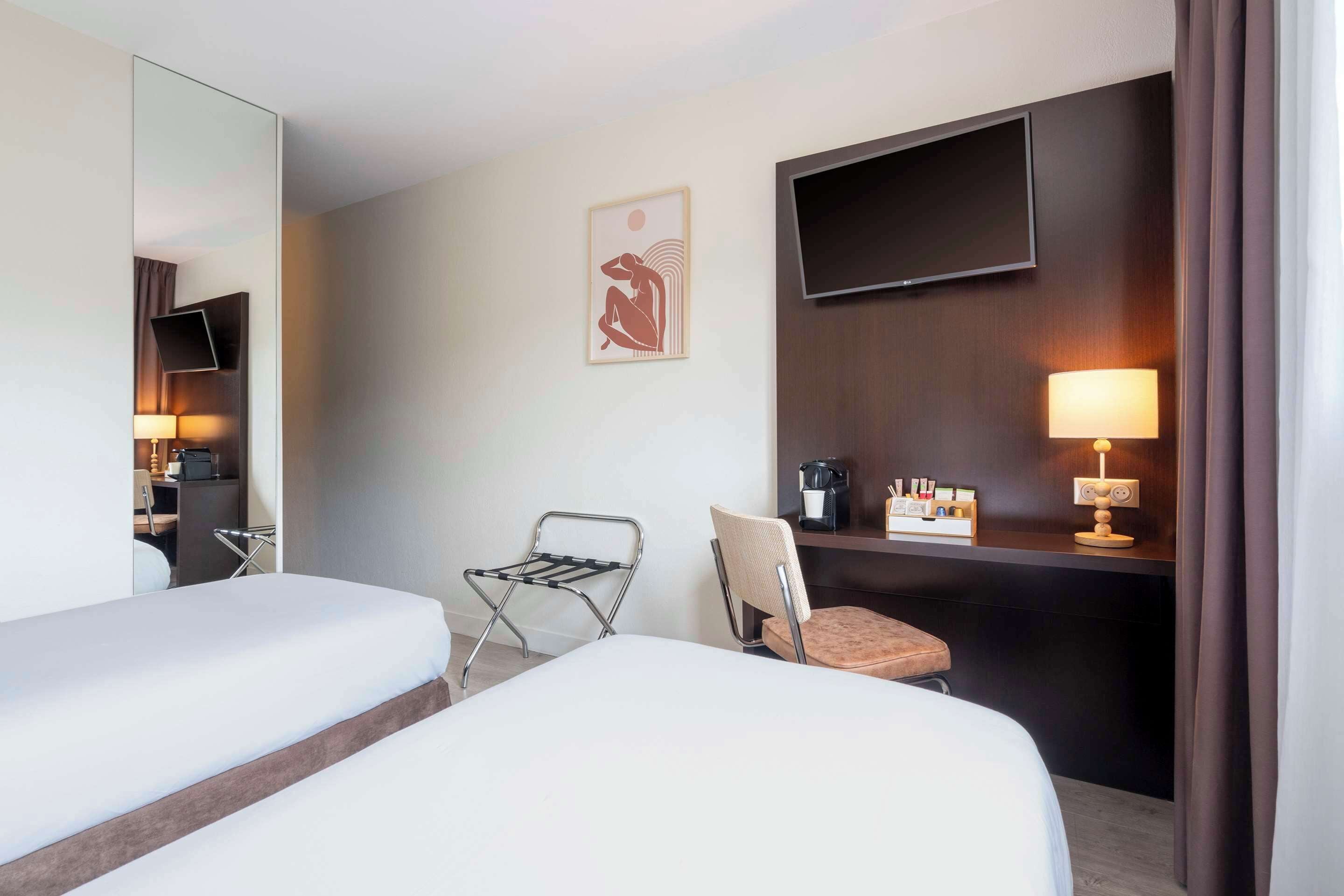A hotel room with two beds, a desk with a chair, a TV, a lamp, and a painting on the wall.
