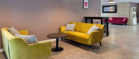 Un área de estar moderna con un sofá y un sillón amarillos, y una pequeña mesa redonda.