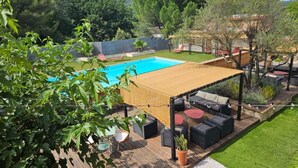 Un jardin avec une piscine, un espace salon extérieur et une pergola.