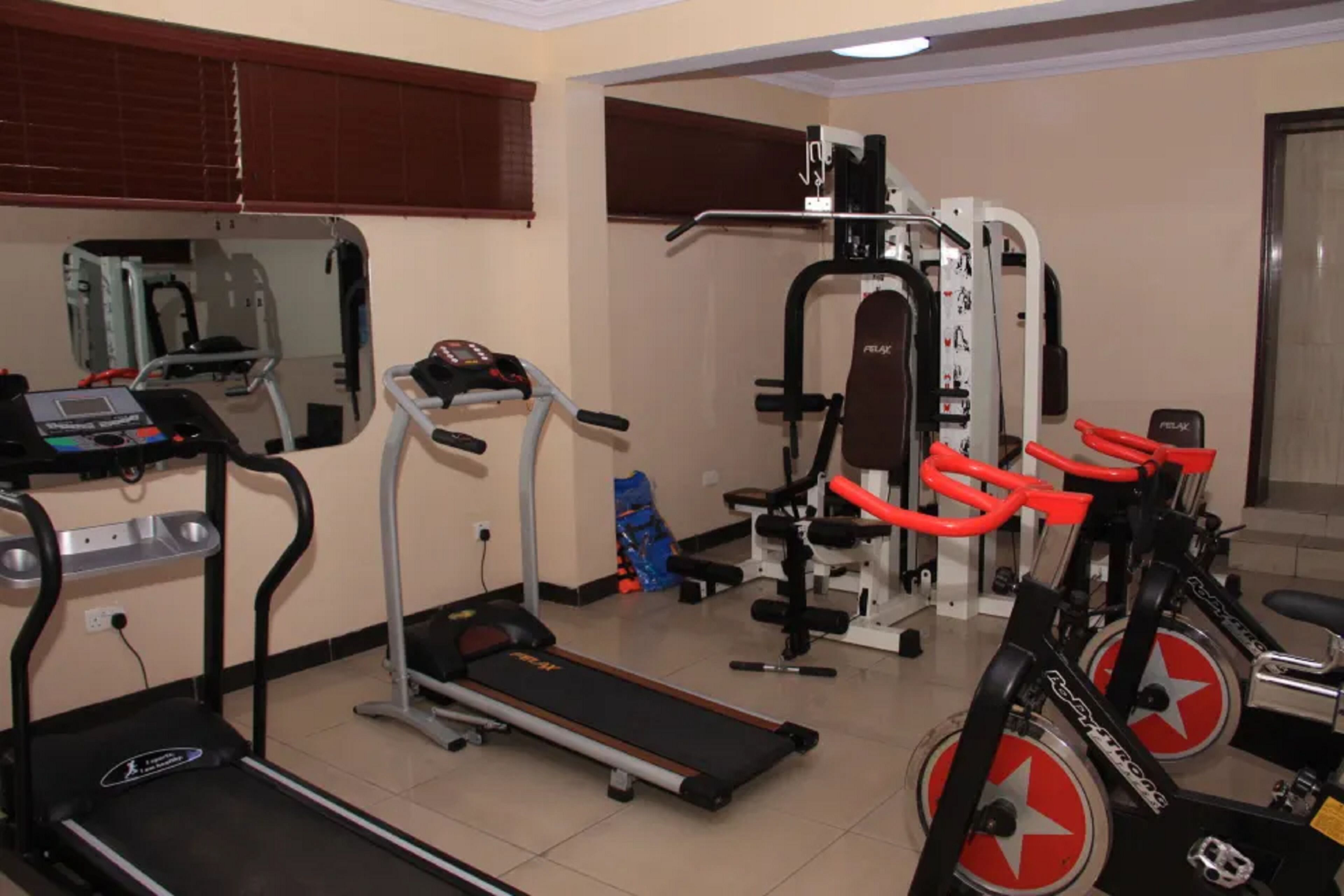 A gym with cardio equipment, weight machines, and a mirror.