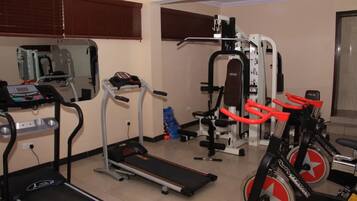 A gym with cardio equipment, weight machines, and a mirror.