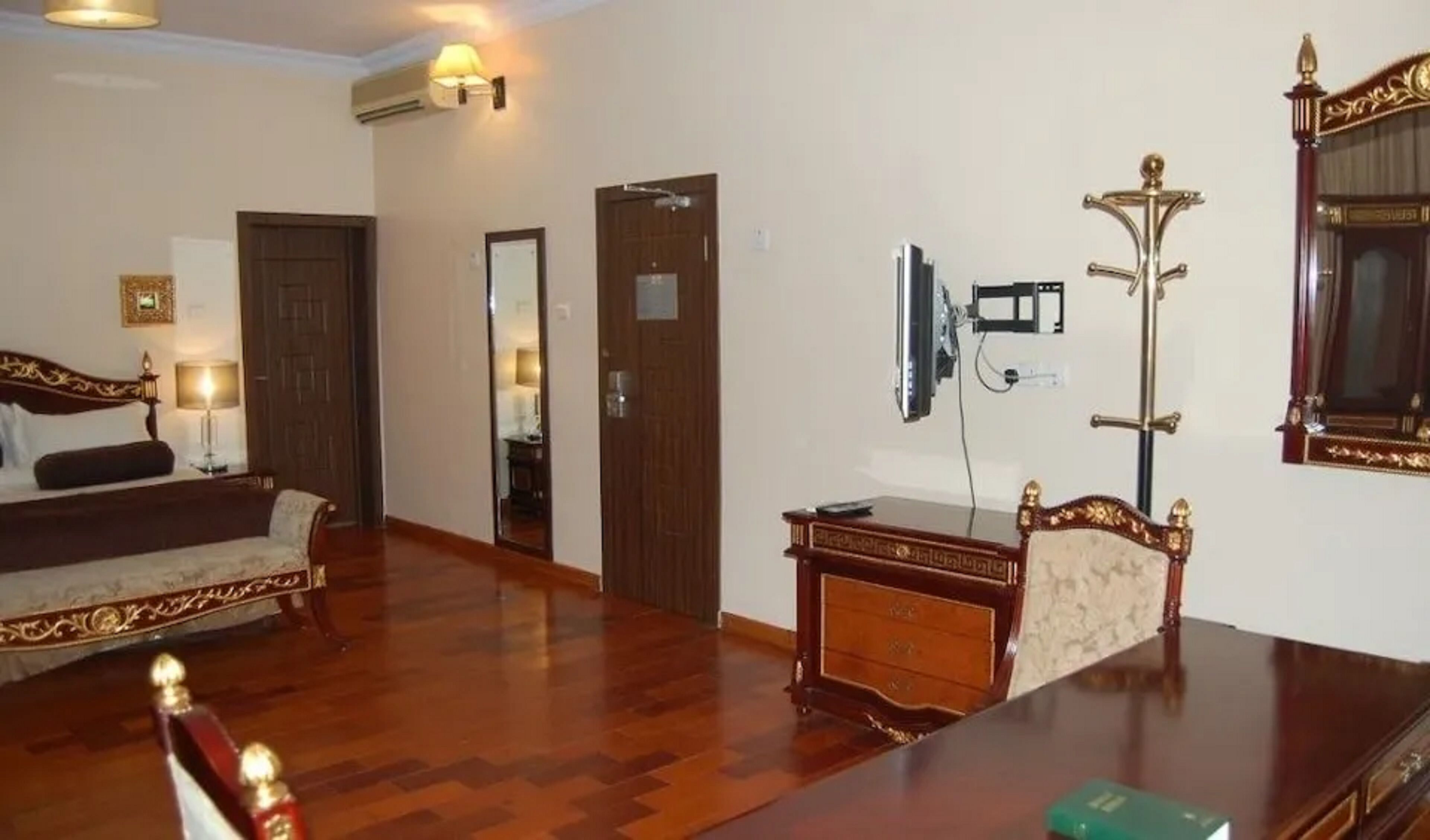 A hotel room with a bed, a desk, a television, and a mirror.