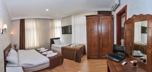 Une chambre d’hôtel avec deux lits, un bureau avec un ordinateur portable, une armoire et un grand miroir.