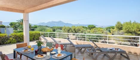 An outdoor dining area with a table set for breakfast, chairs, and a view of the landscape.