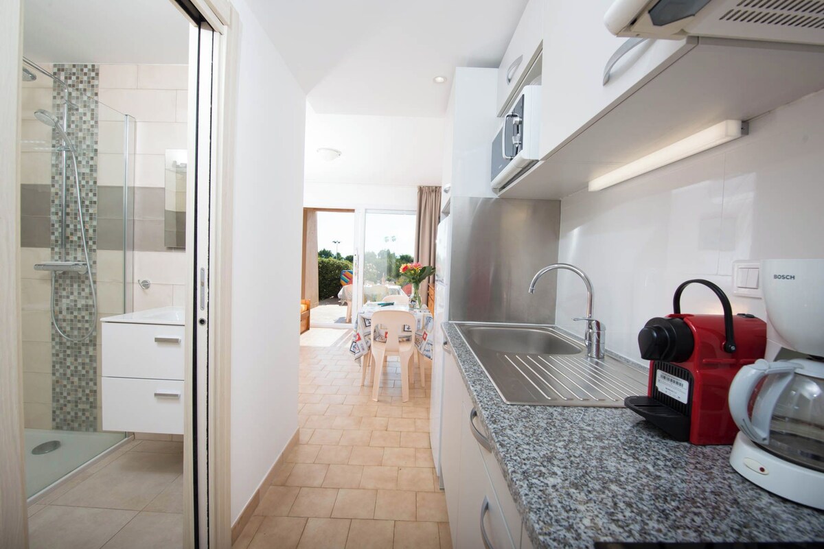 A modern kitchen with a stainless steel sink, a Bosch coffee machine, and a glass shower enclosure.
