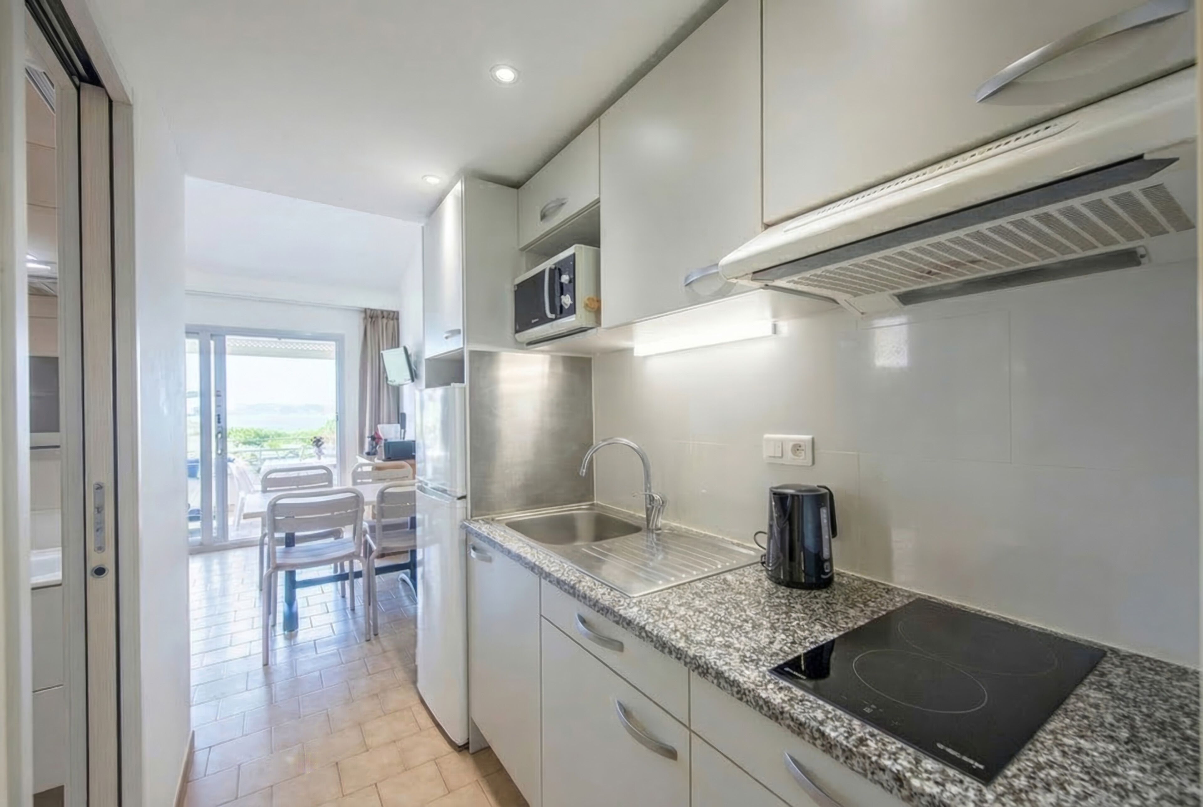 A modern kitchen with stainless steel appliances, a granite countertop, and a view of the outdoor seating area.