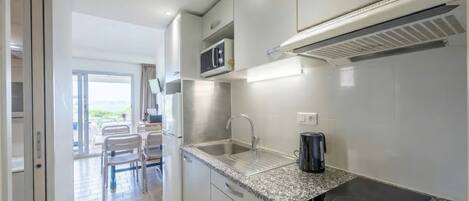 A modern kitchen with stainless steel appliances, a granite countertop, and a view of the outdoor seating area.