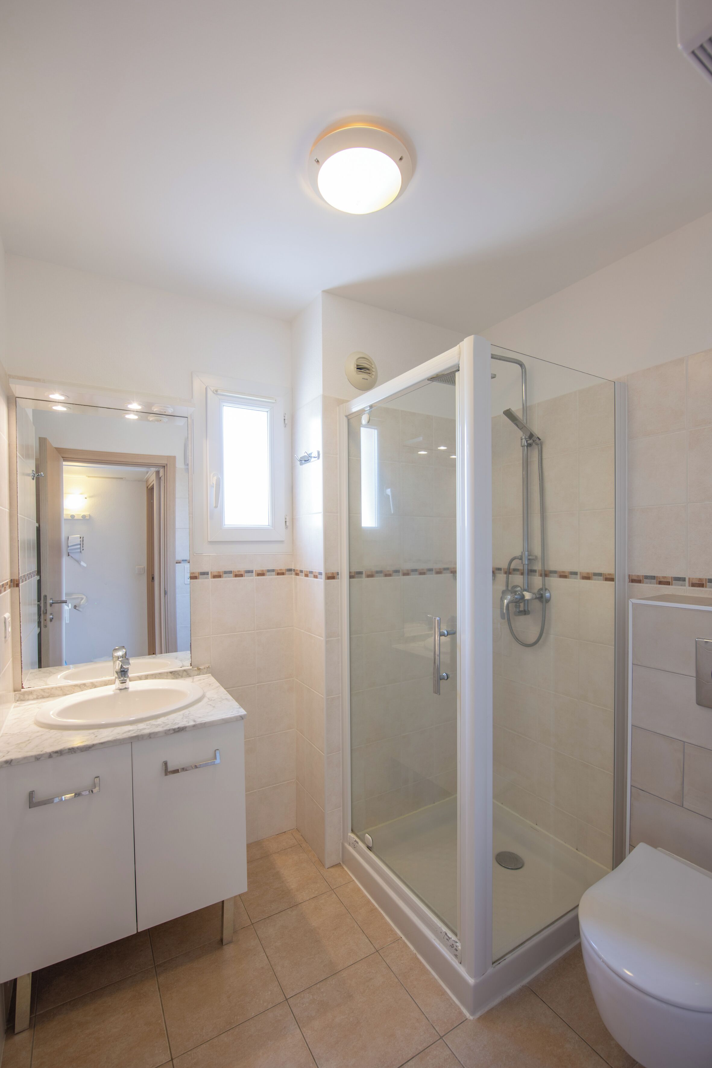 A bathroom with a glass-enclosed shower, a sink with a mirror, and a toilet.
