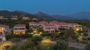 Un resort con varias edificaciones de dos pisos, un camino central y abundante vegetación circundante.