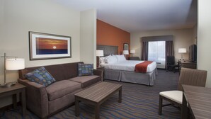 A hotel room with a bed, a sofa, a desk, and a television. - Holiday Inn Express Hotel & Suites Morgan City Tiger Island by IHG (Morgan City)