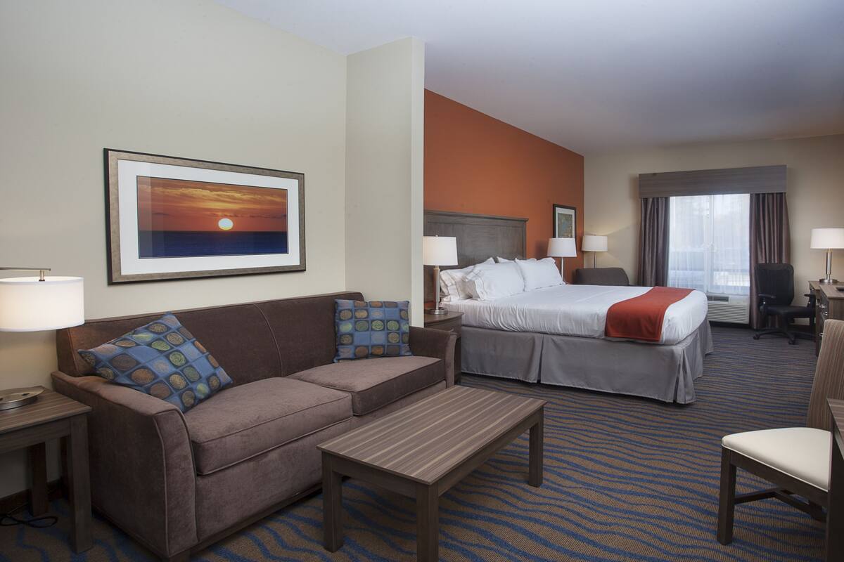 Una habitación de hotel con una cama, un sofá, un escritorio y una televisión.