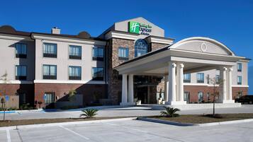 A Holiday Inn Express & Suites hotel with a brick facade, large windows, and a covered entrance.