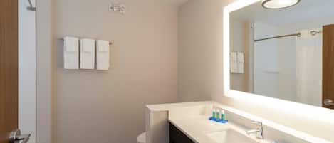 A modern bathroom with a shower, toilet, and a large mirror above the sink.