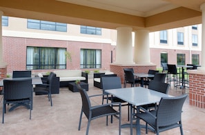 An outdoor patio area with brick walls, multiple tables and chairs, and large windows. - Holiday Inn Express Hotel & Suites Clearfield by IHG (Clearfield)