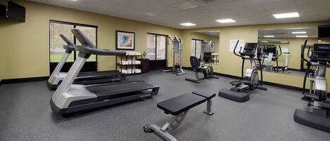 A hotel fitness center with treadmills, elliptical machines, and a bench.