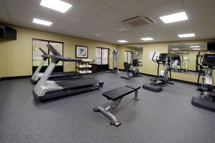 Un gimnasio hotelero con cintas de correr, elípticas y un banco.