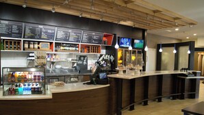 Zona de bar moderna con un tablero de menú, dispensadores de bebidas y una pantalla de televisión.