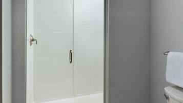 A bathroom with a glass shower enclosure, a white toilet, and a towel rack.
