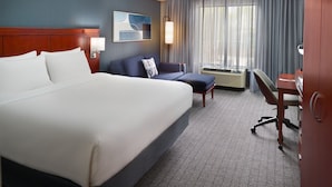 Habitación de hotel con una cama grande, un sofá, un escritorio y un equipo de aire acondicionado.