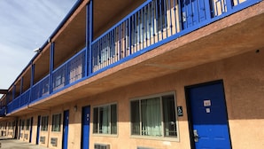 Un motel de varios pisos con balcones de estructura azul y habitaciones individuales con puertas azules.
