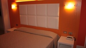 A hotel room with a large bed, a headboard with a padded design, two bedside tables, and a telephone on one of the tables. - Affittacamere Via Mazzini (Stresa)