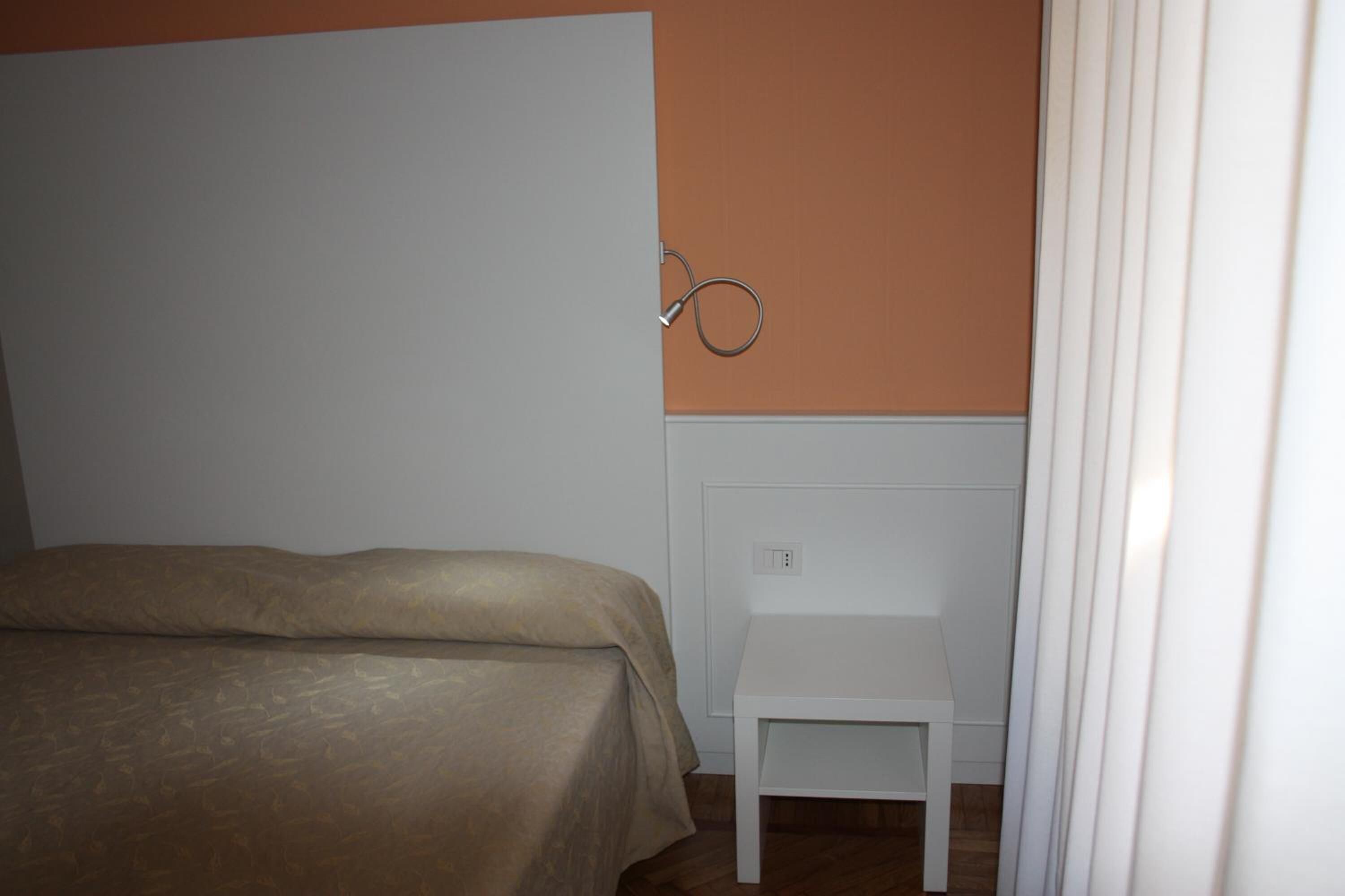 Ein Schlafzimmer mit einem Bett, einem weißen Stuhl und einem Handtuchhalter an der Wand.