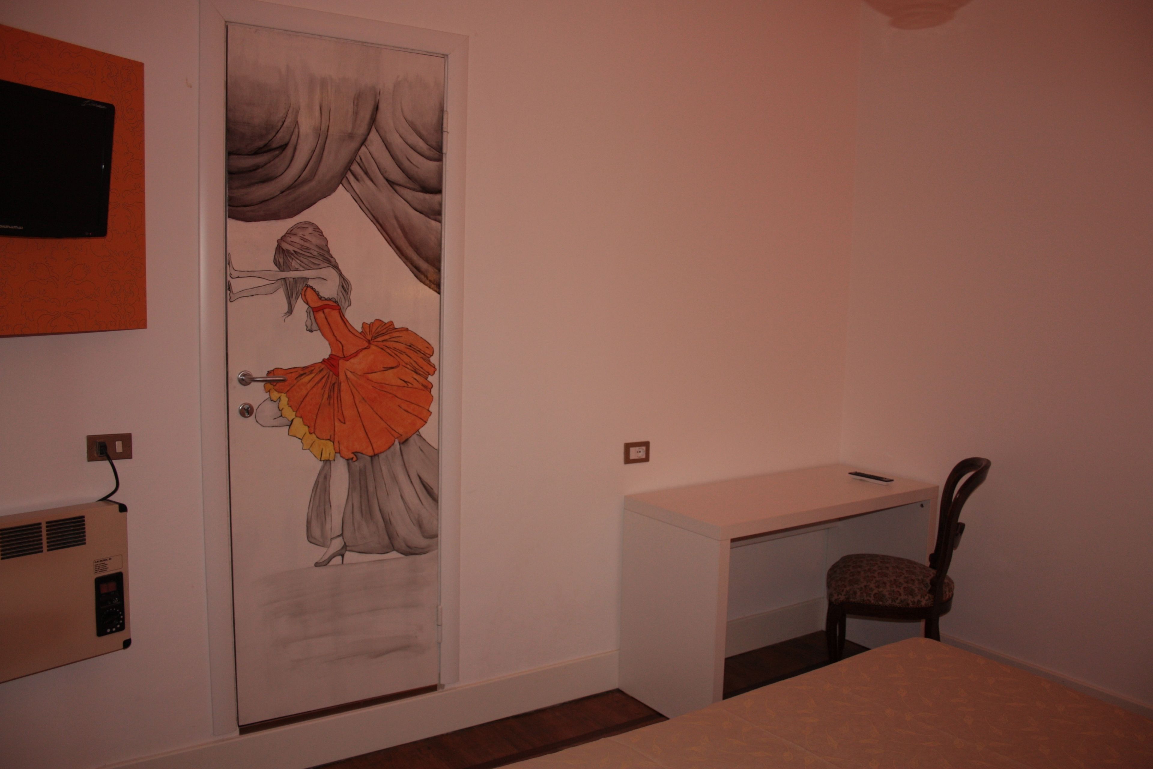 Une pièce comprenant un bureau, une chaise et une porte ornée d’une fresque murale.