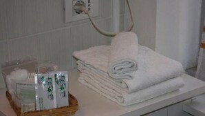 A bathroom with a white towel stack, a basket of toiletries, and a towel rack. - Affittacamere Via Mazzini (Stresa)