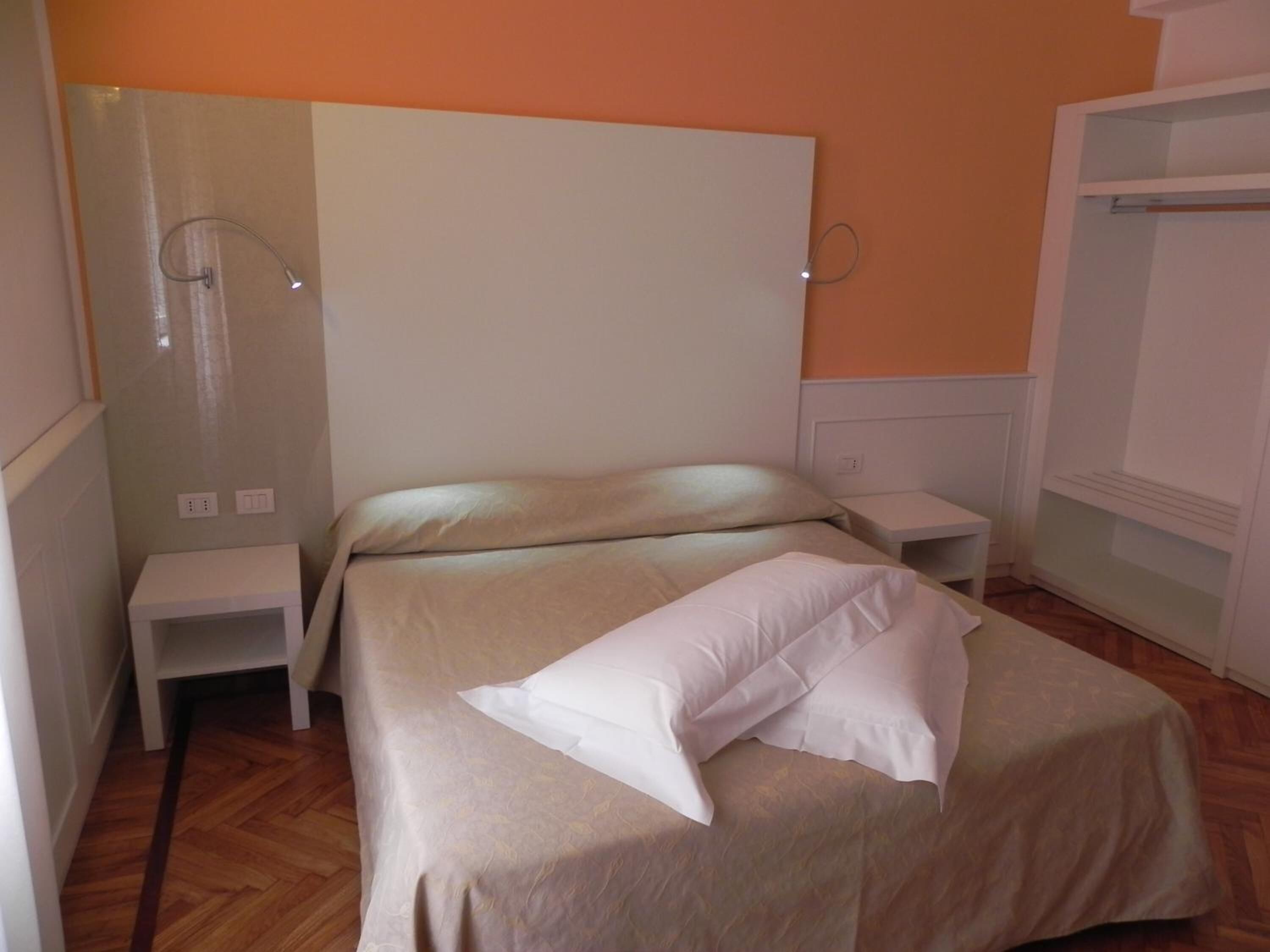 A bedroom with a bed, a nightstand, a wall-mounted lamp, and a wardrobe.