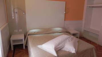 A bedroom with a bed, a nightstand, a wall-mounted lamp, and a wardrobe.