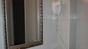 A bathroom with a white sink, a mirror with an ornate frame, a hairdryer mounted on the wall, and a towel rack. - Affittacamere Via Mazzini (Stresa)
