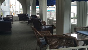 A covered outdoor seating area with wicker furniture and a view of the street. - Blue Water Inn (Ocean City)