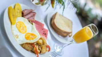A breakfast plate with eggs, ham, potatoes, and toast, accompanied by a glass of orange juice.