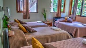A hotel room with two beds, each with a pillow and a small table. - Hotel Jaguar Inn Tikal (Flores)