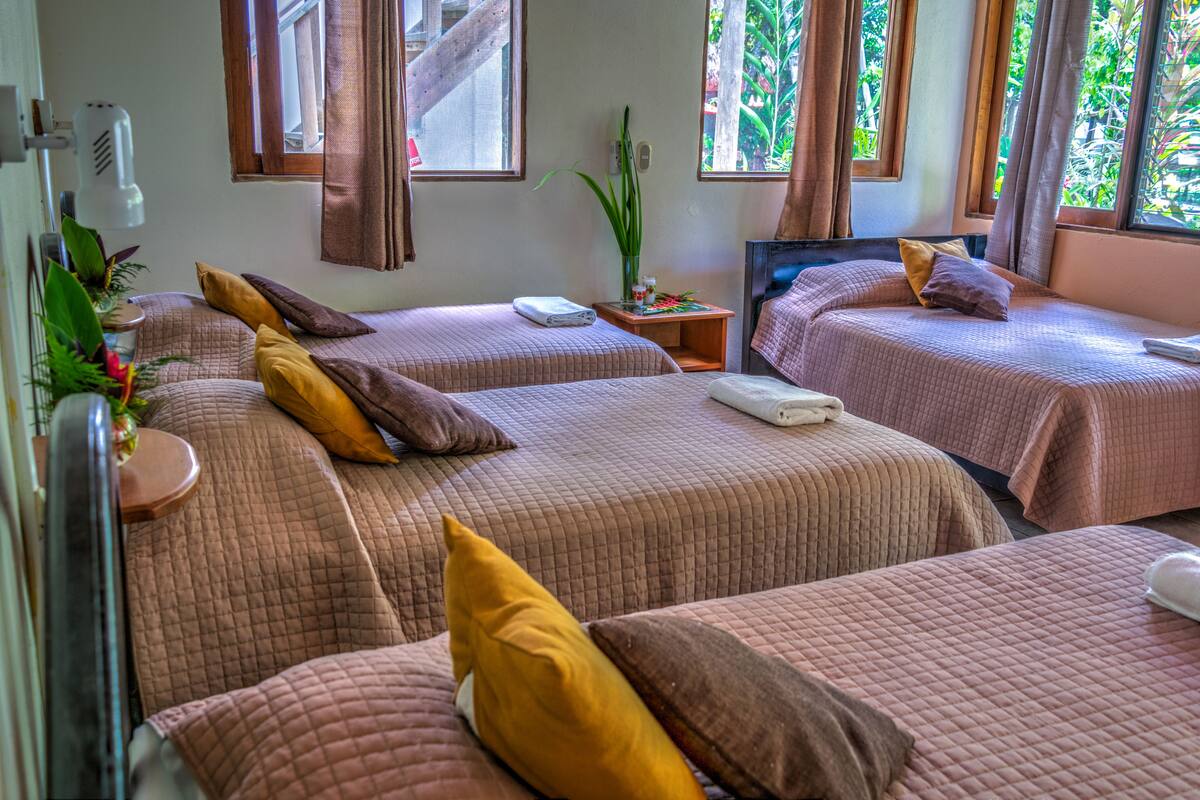 A hotel room with two beds, each with a pillow and a small table.