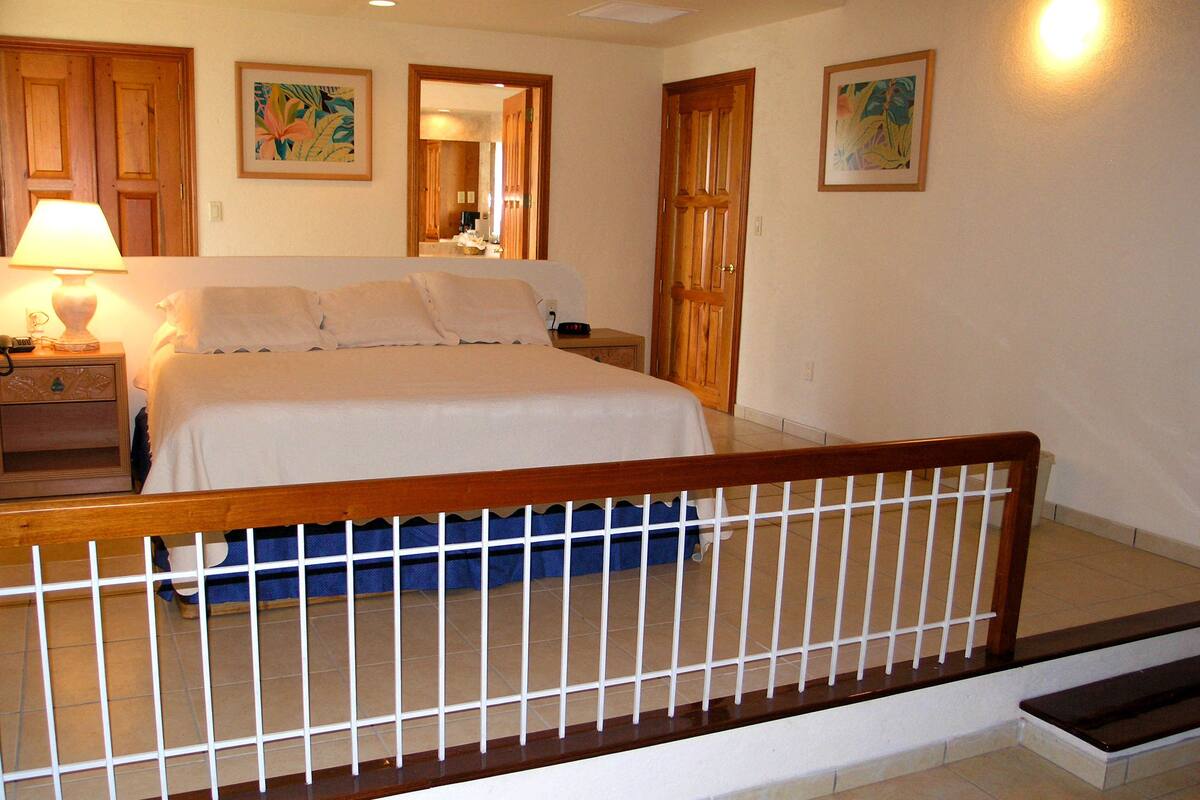 A hotel room with a bed, nightstand, lamp, and artwork on the walls.