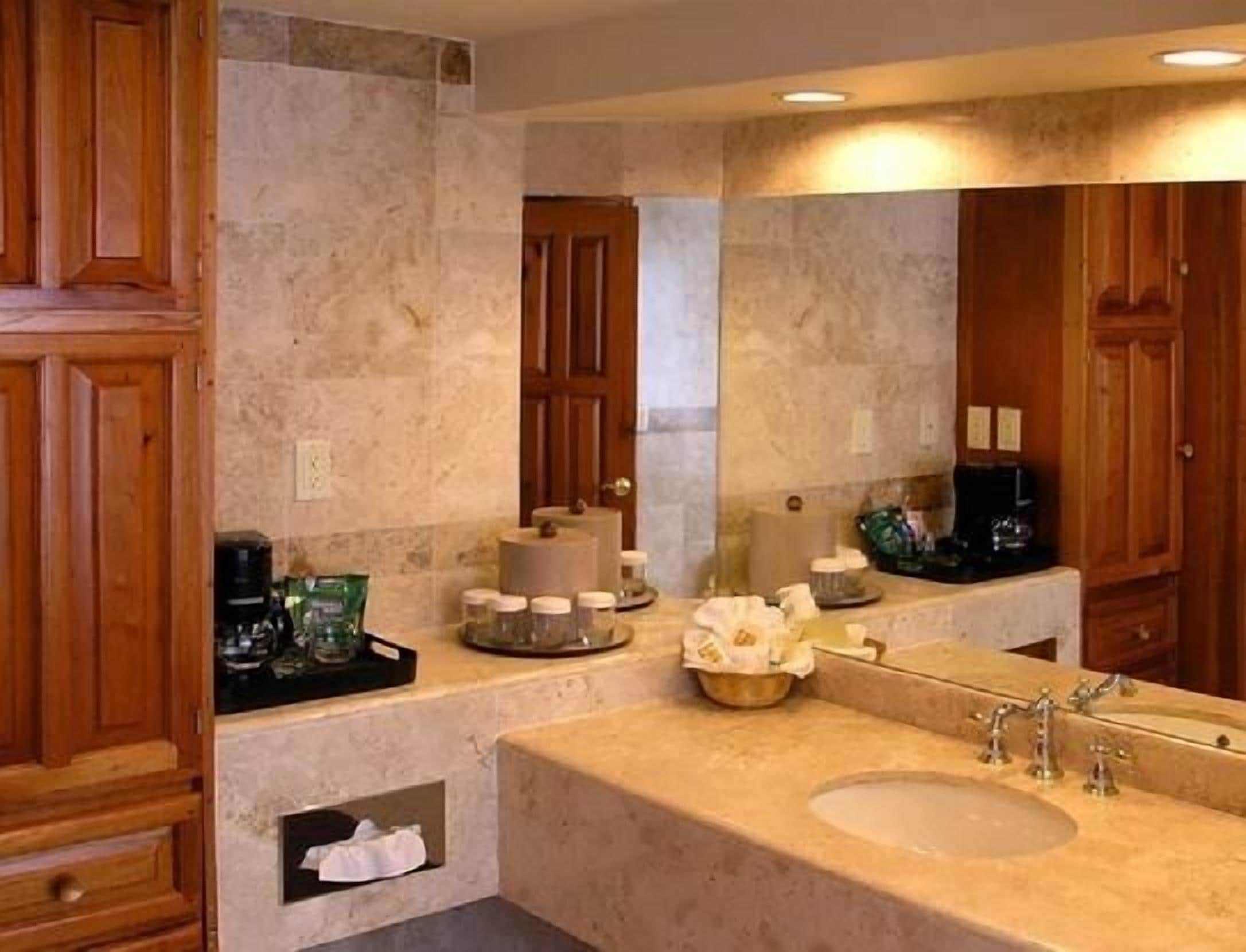 A bathroom with a large sink, wooden cabinets, and a mirror.