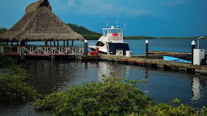 Um cais com uma cabana de telhado de palha, um barco de pesca e um pequeno barco azul.