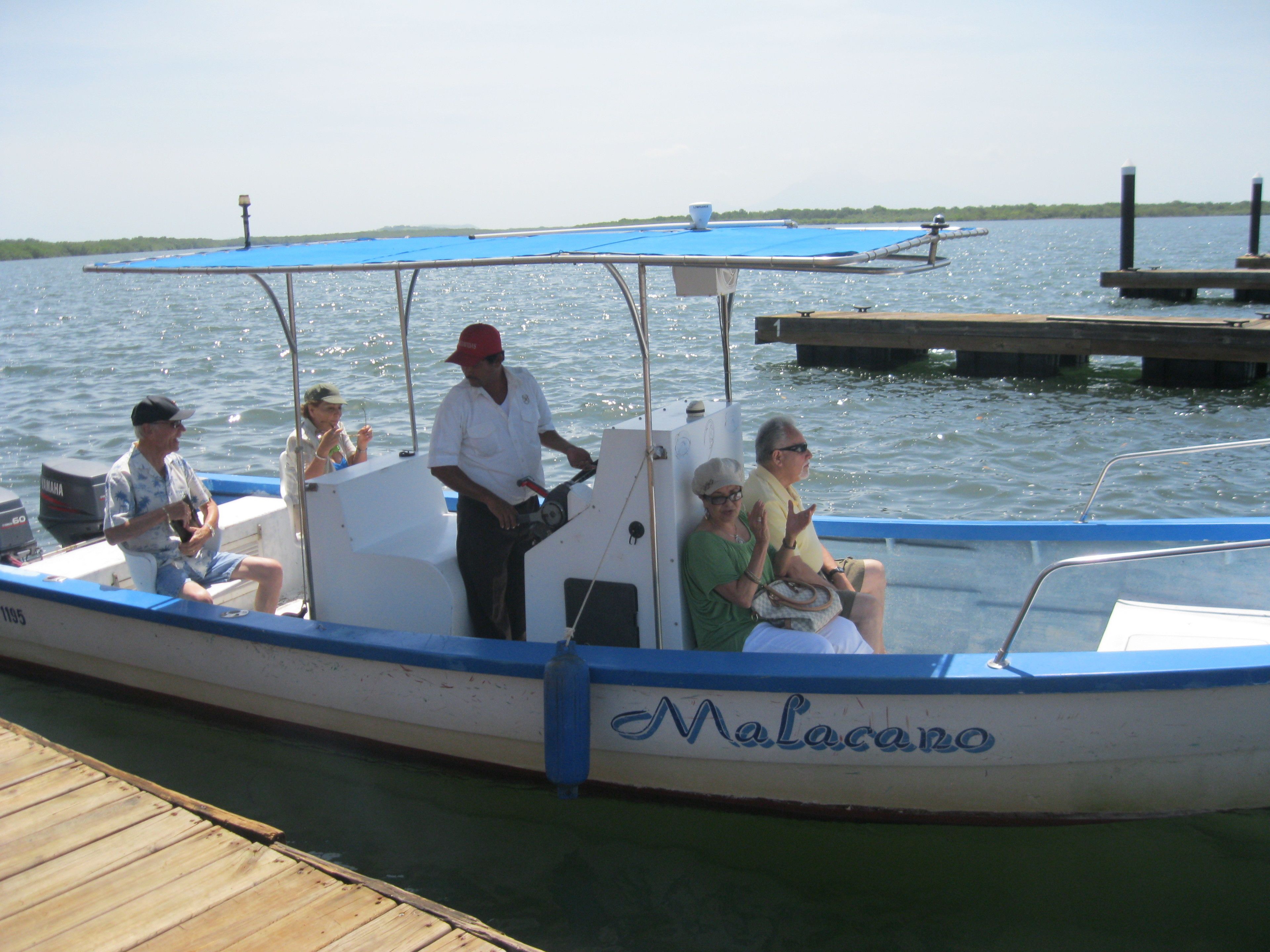 A boat with the name "Malacano" docked at a wooden pier.