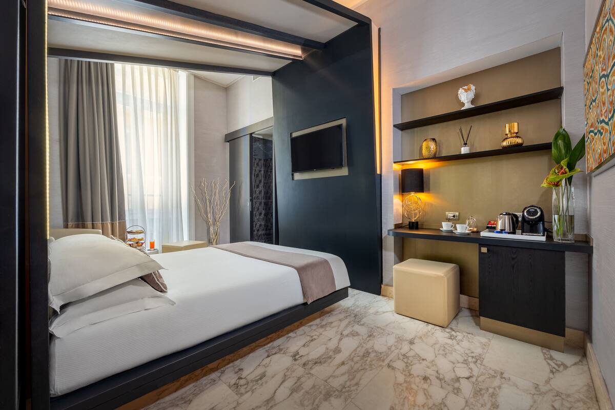 A modern hotel room with a large bed, a desk, and a TV.
