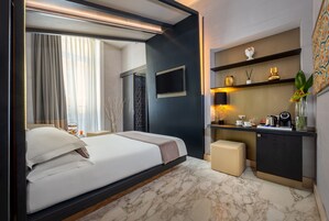 A modern hotel room with a large bed, a desk, and a TV.
