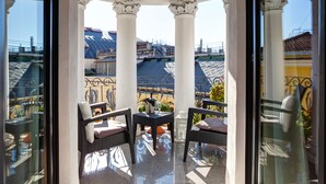 A balcony with two wicker chairs, a small table, and a glass railing. -  Dharma Luxury Hotel & Spa. (Rome)