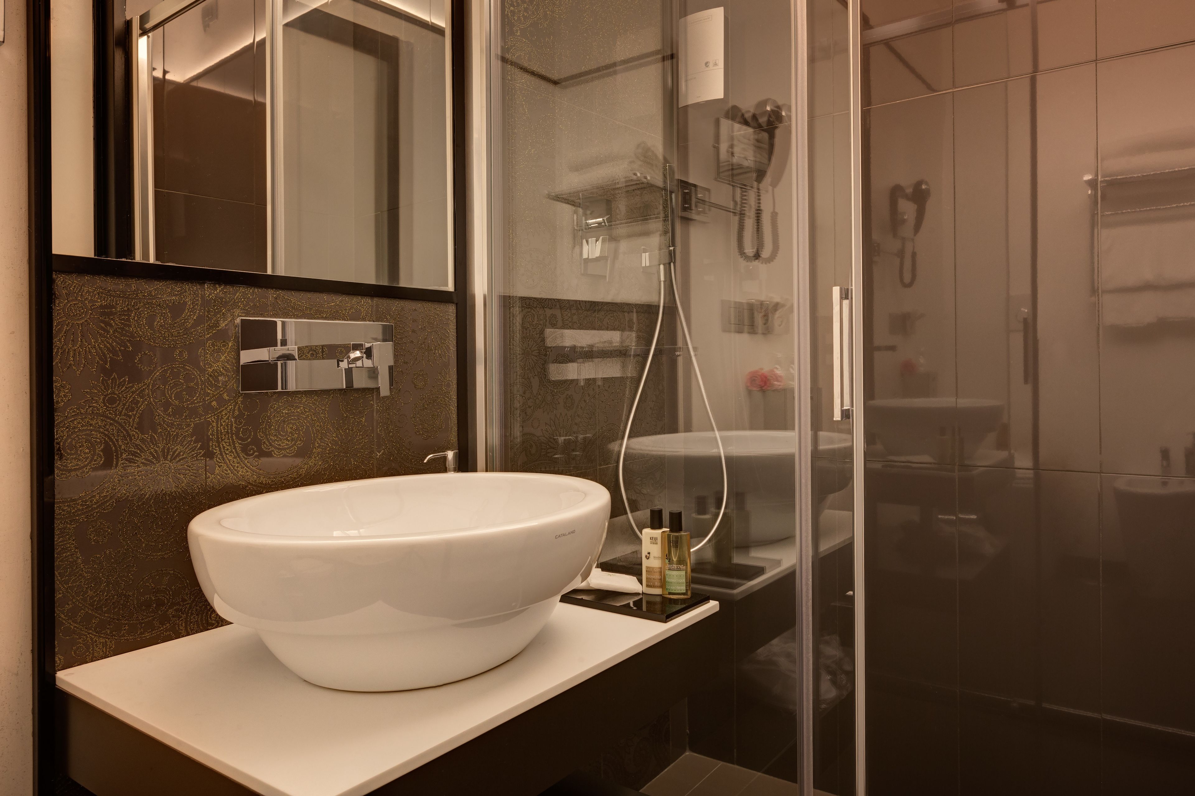 Un baño moderno con un lavabo blanco de diseño, una cabina de ducha de vidrio y un espejo sobre el lavabo.