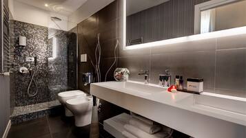 Un bagno moderno con doccia vetrata, un water bianco e un grande specchio sopra un mobile lavabo bianco dotato di portasciamani.